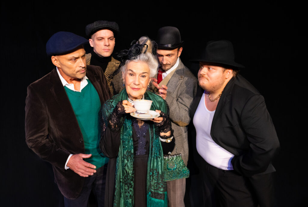 Die alte Lady mit Teetasse umringt von den 4 Killern