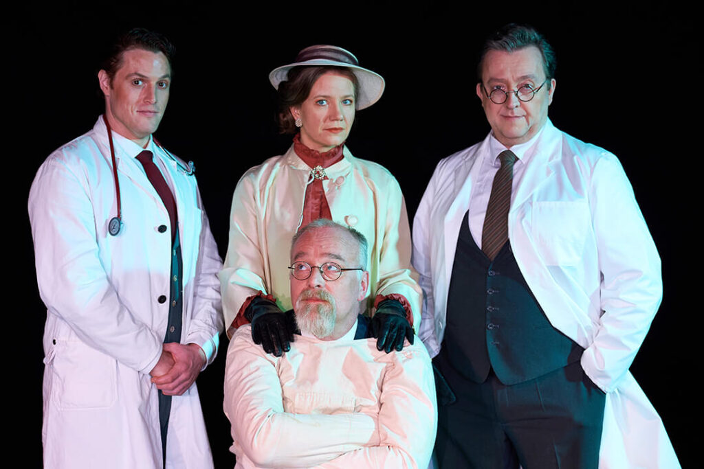 3 Männer und eine Frau, ein Mann sitzend, die drei anderen hinten dran stehend